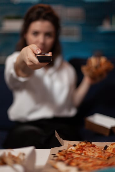 closeup-view-woman-hand-holding-television-remote-control-change-volume-while-having-delivery-pizza-dinner-living-room-detail-person-browsing-tv-channels-while-eating-burger